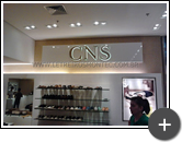 Letreiro da loja CNS de calçados em aço inox polido e iluminado por leds em ambiente interno